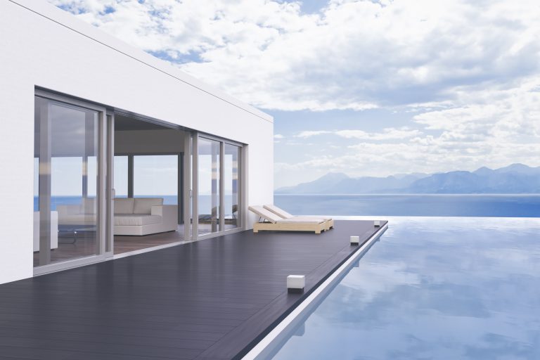 Minimalist modern villa exterior with infinity pool and beautiful ocean view.